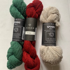 以下が含まれることがあります： 緑、赤、自然色の3つの糸巻き。糸は「Spinni Wool 1」とラベル付けされており、100% 天然ウールです。糸はIsager製です。