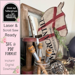 May include: A rustic wooden horse head with red cross design and the word "MERCANTILE" in black. The image includes vintage spools, a red-topped wooden object, and text that reads "Laser & Scroll Saw Ready" and "SVG & PDF FORMAT".