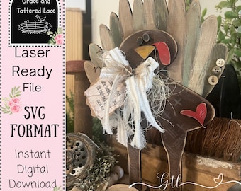 May include: A rustic wooden turkey decoration with a brown body, a red heart, and a fan of green and brown feathers. It has a bow with a tag that reads "The Lord is good". The text "Laser Ready File SVG Format Instant Digital Download" is on the left.