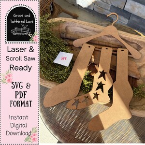 May include: Laser cut wooden sock cutouts, including one with star cutouts, a wooden hanger, and the text "Laser & Scroll Saw Ready SVG & PDF FORMAT Instant Digital Download". A small white card has the number "388".