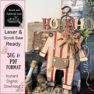 May include: A wooden cutout of a pair of overalls with red and white vertical stripes, white snowflake patterns, and a brown pocket. The piece features the text HOHOHO at the top, a fabric bow, and green pine needles. It is designed for laser and scroll saw use.