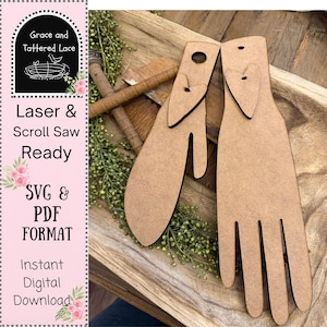 May include: Two wooden hand-shaped cutouts with a hole at the top for hanging. The cutouts are light brown and are displayed on a wooden tray with greenery. The image also includes text that reads "Grace and Tattered Lace", "Laser & Scroll Saw Ready", "SVG & PDF FORMAT", and "Instant Digital Download."