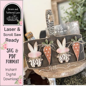 May include: A wooden Easter-themed cutting board with a handle, featuring two bunny and carrot cutouts. The bunnies have pink ears and are paired with orange carrots. The board has a dark brown finish and is decorated with twine.