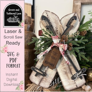 May include: Wooden decorative skis with black metal bindings and a "Ski Pass" tag. The skis are adorned with greenery, pinecones, and a red and white fabric bow. The image also includes text that says "Laser & Scroll Saw Ready" and "SVG & PDF FORMAT".