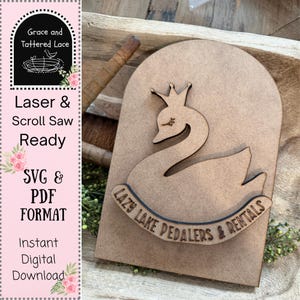 May include: A laser-cut wooden sign featuring a swan wearing a crown, with the text "Lazy Lake Pedalers & Rentals" below. The sign is ready for laser and scroll saw projects, available in SVG and PDF formats for instant digital download.