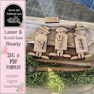 May include: Three wooden snowman cutouts with different hat styles and decorative elements. The cutouts are placed on a wooden surface with a broom and greenery. The number "258" is also visible. The image also includes the text "Laser & Scroll Saw Ready" and "SVG & PDF FORMAT".