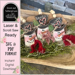May include: Wooden snowman ornaments with black top hats, pink and white striped bodies, and carrot noses. Each ornament has a sign that says "Santa's" or "North". The image also includes the text "Laser & Scroll Saw Ready" and "SVG & PDF FORMAT".
