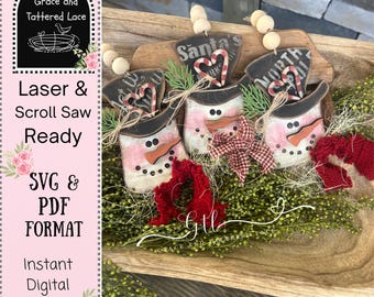 May include: Wooden snowman ornaments with black top hats, pink and white striped bodies, and carrot noses. Each ornament has a sign that says "Santa's" or "North". The image also includes the text "Laser & Scroll Saw Ready" and "SVG & PDF FORMAT".