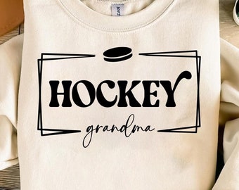 May include: A cream-colored sweatshirt with a black graphic design that says "HOCKEY grandma" with a hockey puck above the text.