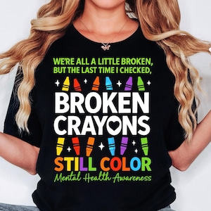 May include: Black t-shirt with the text "We're all a little broken, but the last time I checked, broken crayons still color." and the text "Mental Health Awareness". The shirt features a design of colorful crayons.