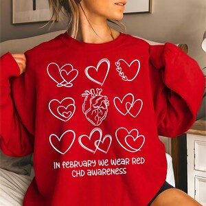 May include: Red sweatshirt with a white graphic of hearts and the text "In February we wear red CHD awareness".