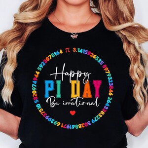 Może przedstawiać: Czarny T-shirt z kolorowym wzorem koła przedstawiającym cyfry pi i tekst "Happy Pi Day Be irrational".