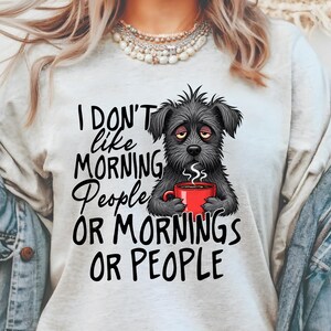 Peut inclure: T-shirt gris clair avec une illustration noire d'un chien fatigué tenant une tasse de café rouge. Le texte sur le t-shirt dit "I don't like morning people or mornings or people."