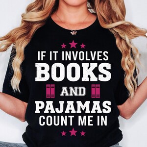 Peut inclure: T-shirt noir avec l'inscription blanche "IF IT INVOLVES BOOKS AND PAJAMAS COUNT ME IN". Le motif comprend des étoiles roses et des illustrations de livres. Un t-shirt décontracté pour les amateurs de livres et de détente.