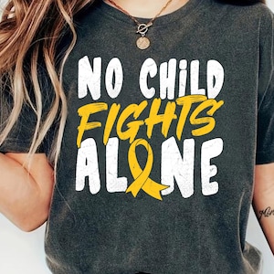 May include: Dark gray t-shirt with the text "NO CHILD FIGHTS ALONE" in white and yellow. A yellow ribbon graphic is below the text. The shirt is a casual style.