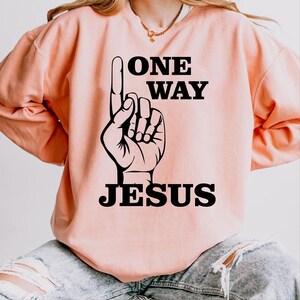 May include: A peach-colored sweatshirt with a black graphic of a hand pointing up with the text "ONE WAY JESUS".
