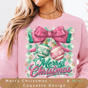 Puede incluir: Sudadera rosa con temática navideña con un gran lazo rosa y dos adornos colgantes. Los adornos son verdes y rosas con diseños de copos de nieve. Las palabras "Merry Christmas" están escritas en cursiva. El fondo tiene un patrón de cuadros verdes y blancos.