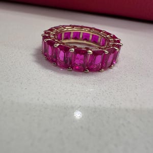 May include: A gold ring with a band of pink rectangular stones.