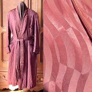 May include: A long, burgundy robe with a patterned design. The robe has a shawl collar, a sash tie, and two pockets.
