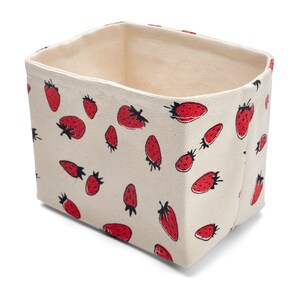 May include: A cream-colored canvas storage bin with a red strawberry pattern. The bin is empty and has a rectangular shape.