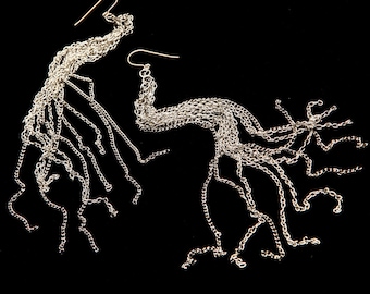 May include: A pair of silver dangle earrings with multiple chains hanging from the bottom. The chains are all different lengths and create a cascading effect.