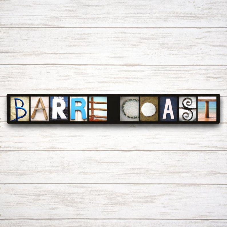 Puede incluir: Un letrero rectangular negro con la palabra "BARRE COAST" deletreada en bloques de letras individuales. Cada bloque de letras tiene un dise&ntilde;o &uacute;nico, incluyendo im&aacute;genes del oc&eacute;ano, conchas y madera.
