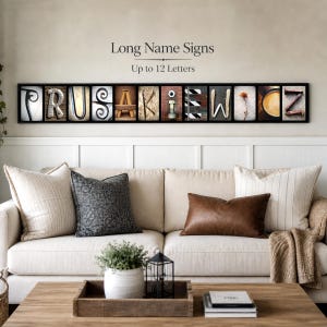 Puede incluir: Una obra de arte mural enmarcada con bloques de letras individuales que deletrean un nombre. Cada letra tiene un dise&ntilde;o &uacute;nico, con el texto "Long Name Signs" y "Up to 12 Letters" encima de las letras. La obra de arte cuelga sobre un sof&aacute; color crema.