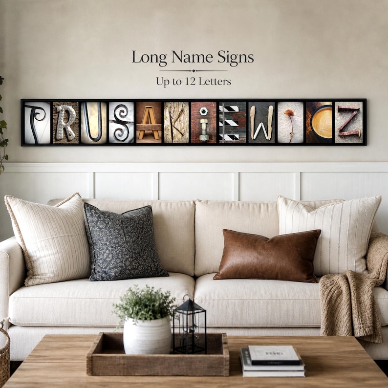 Puede incluir: Una obra de arte mural enmarcada con bloques de letras individuales que deletrean un nombre. Cada letra tiene un dise&ntilde;o &uacute;nico, con el texto "Long Name Signs" y "Up to 12 Letters" encima de las letras. La obra de arte cuelga sobre un sof&aacute; color crema.