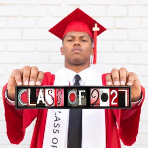 Puede incluir: Un marco negro rectangular que contiene una serie de im&aacute;genes cuadradas que forman el texto CLASS OF 2027. Cada letra y n&uacute;mero est&aacute; formado por objetos que se asemejan a los caracteres, sobre un fondo rojo y blanco con tem&aacute;tica de graduaci&oacute;n.