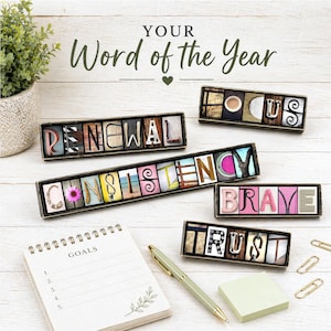 May include: Wooden framed word art spelling out "RENEWAL", "CONSISTENCY", "FOCUS", "BRAVE", and "TRUST". The words are made of various textured letters. A notepad, pen, and small plant are also present. The text "YOUR Word of the Year" is at the top.