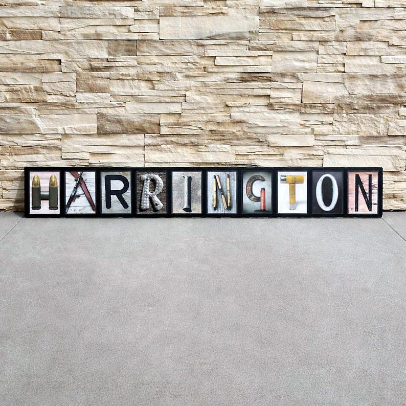 Puede incluir: Una obra de arte enmarcada que deletrea "HARRINGTON" con letras individuales. Cada letra est&aacute; rellena con diferentes objetos, incluyendo balas, madera y herramientas. El marco es negro y el fondo es una pared de piedra texturizada.