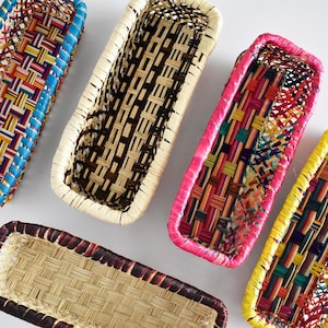 May include: Five woven rectangular baskets with colorful trim. The baskets are made of natural materials and have a variety of colors and patterns.