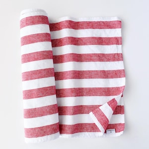 May include: Red and white striped linen fabric rolled up. The fabric is a soft, natural material with a subtle texture.