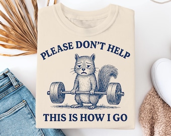 Peut inclure: Sweat-shirt crème avec un dessin vieilli d'un écureuil soulevant des poids. Le texte au-dessus de l'écureuil dit "PLEASE DON'T HELP", et en dessous, "THIS IS HOW I GO". Le design est bleu marine.