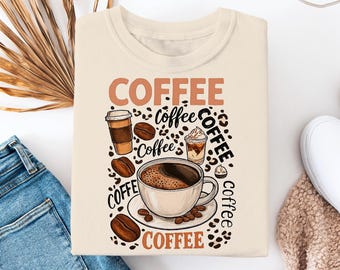 Puede incluir: Sudadera de color crema con un gráfico temático de café. El diseño incluye la palabra "COFFEE" en una fuente marrón con estampado de leopardo, junto con tazas de café, granos y la palabra "coffee" en varias fuentes. La sudadera está doblada sobre una superficie blanca.