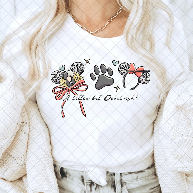 K&ouml;nnte beinhalten: Wei&szlig;es T-Shirt mit einem Cartoon-Design mit einem Hund, einem Pfotenabdruck und Minnie-Maus-Ohren. Das Design enth&auml;lt eine rosa Schleife und den Text "A little bit Devil-ish!"