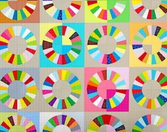 Puede incluir: Una colcha colorida con un patrón repetitivo de círculos hechos de tiras de tela de diferentes colores. Cada círculo está dividido en 12 secciones, creando un diseño radial.