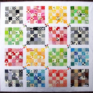 May include: A colorful quilt made of many small squares of fabric. The squares are arranged in a rainbow pattern, with each row of squares featuring a different color. The quilt is made with a variety of fabrics, including polka dots, stripes, and floral prints.