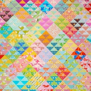 Puede incluir: Una colcha colorida hecha de triángulos de tela de patchwork en varios patrones y colores, incluyendo rosa, azul, verde, amarillo y naranja.