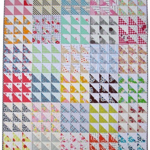 Op de afbeelding: Een quilt gemaakt van kleurrijke vierkanten stof met een patroon van driehoeken. De quilt is gemaakt van 40 vierkanten, elk met een ander patroon. De quilt is een patchwork van verschillende stoffen, waaronder bloemenprints, geometrische patronen en effen kleuren.