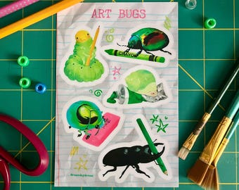 May include: A sheet of stickers with the text "ART BUGS" features illustrations of insects with art supplies. The stickers include a green caterpillar with a pencil, a green beetle with a crayon, and a black beetle with a pencil.