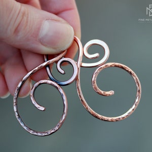 May include: A hammered copper wire hair comb with a triple swirl design. The comb is made by Fine Metal Dust.