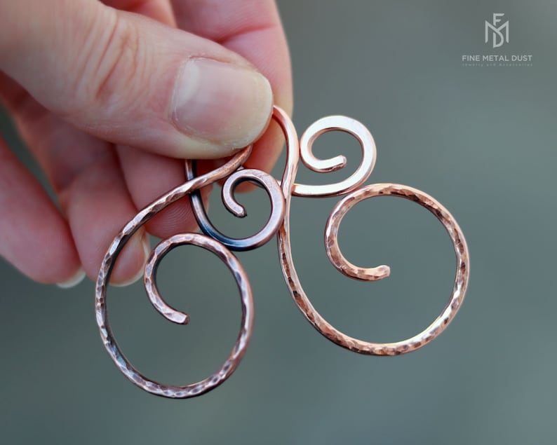 May include: A hammered copper wire hair comb with a triple swirl design. The comb is made by Fine Metal Dust.
