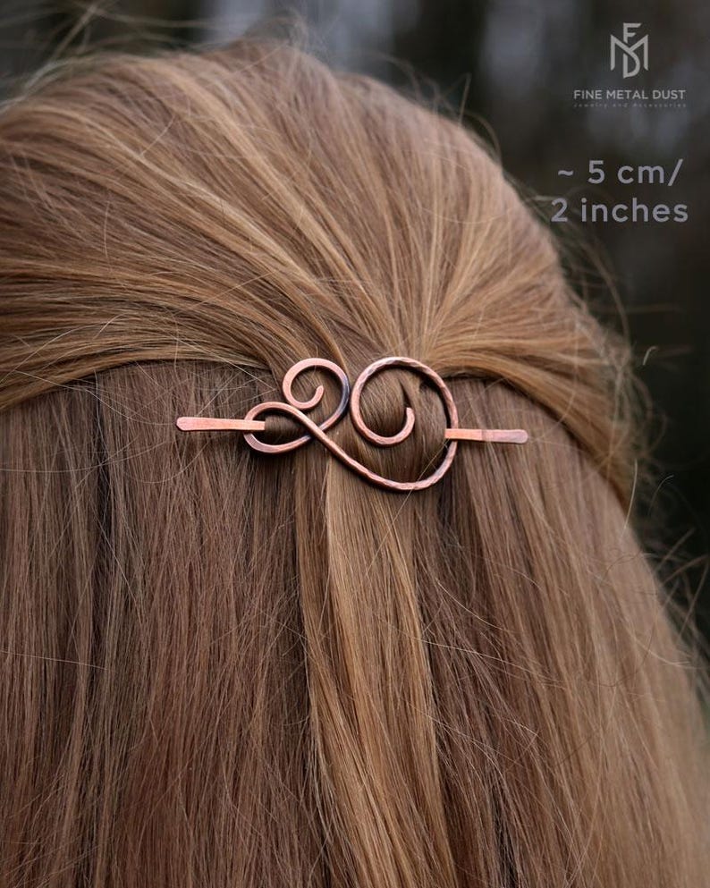 May include: A copper hair clip with a swirling design. The clip is about 5 cm or 2 inches long.