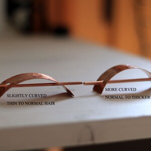 May include: Two copper hair sticks, one slightly curved and the other more curved. The slightly curved stick is labeled "Slightly Curved, Thin to Normal Hair" and the more curved stick is labeled "More Curved, Normal to Thicker Hair".
