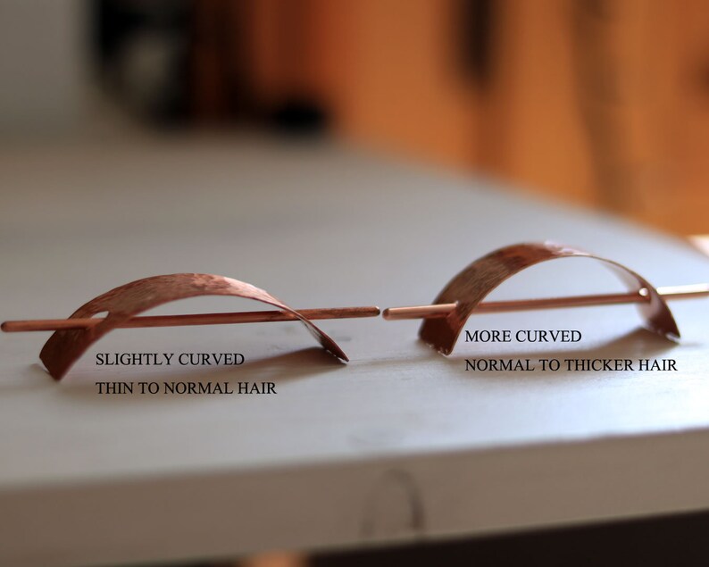May include: Two copper hair sticks, one slightly curved and the other more curved. The slightly curved stick is labeled "Slightly Curved, Thin to Normal Hair" and the more curved stick is labeled "More Curved, Normal to Thicker Hair".