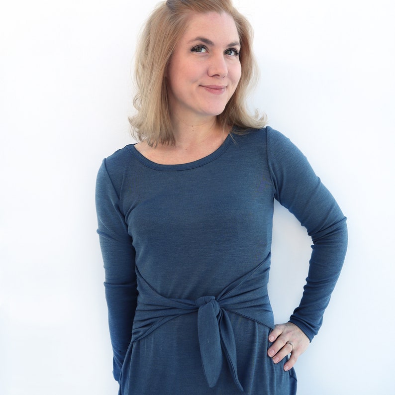 Puede incluir: Un vestido azul de manga larga con un lazo en la cintura.