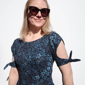 Puede incluir: Un vestido de estampado floral azul y negro con mangas cortas que se atan en la mu&ntilde;eca. El vestido tiene un escote redondo y un corte holgado.