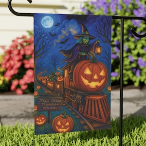 May include: A Halloween garden flag featuring a witch riding a pumpkin train under a full moon. The flag has a dark blue background with bats, trees, and jack-o'-lanterns. The text on the sign reads "Magic Ahead Tricksters Welcome."