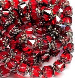 May include: Close-up of a strand of faceted, deep red beads. Each bead has a square shape with multiple facets, creating a sparkling effect. The beads are strung together with silver-colored metal accents, creating a jewelry component.